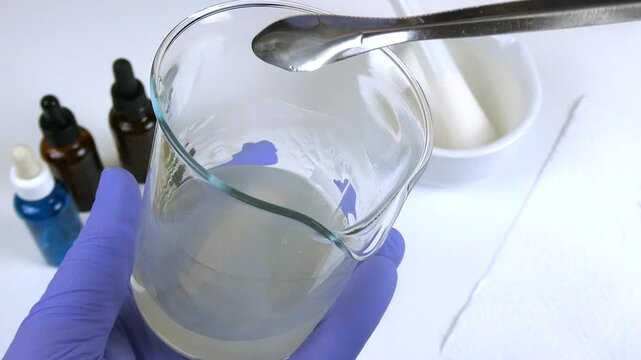 Scientist in purple gloves preparing a cosmetic serum formulation in a scientific laboratory