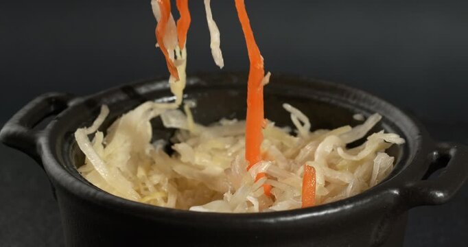 Bowl of fermented cabbage with parsley and carrots, sauerkraut, sauer kraut, a healthy vegan crunchy probiotic. Sauerkraut is picked up with a fork.