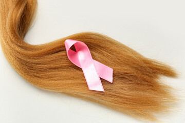 Red hair strand for donation with pink awareness ribbon on white background