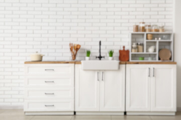 Stylish interior of kitchen with sink, white counters and shelving unit, blurred view