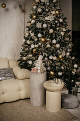 White soft sofa, table and lamp on the background of a decorated Christmas tree inside a photo studio for a photo shoot
