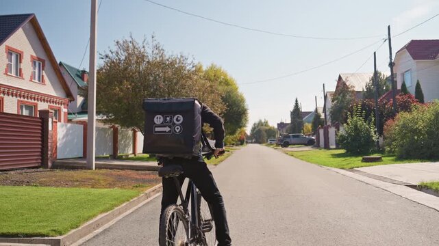 courier pedaling through treelined suburban street, riding electricassisted bicycle with insulated delivery box, passing houses with gardens and trimmed hedges, bright morning light, swift confident