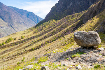 Black stone boulder on mountain with view of Chulyshman valley Altai Russia Sacred natural landmark and spiritual site