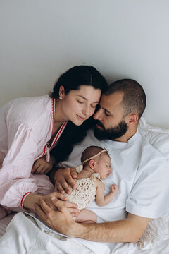 A family of three rests together in a calm, loving moment at home