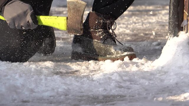 Snow removal, a man in the yard chipping away ice. Winter chores, clearing ice from the yard.