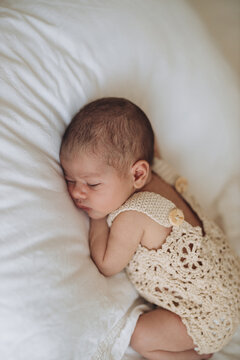 Newborn baby sleeping peacefully on a soft white pillow in a cozy, natural light setting