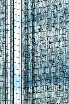 Modern corporate office skyscraper architecture facade with glass windows pattern behind metal lattice mesh on urban building background texture