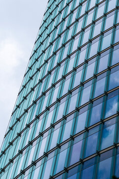 Modern corporate office skyscraper architecture facade with blue glass windows pattern on slanted building corner creating clean abstract background