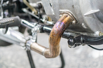 Close-up of worn, rusted exhaust pipe on vintage motorcycle, shot from above in an industrial setting High contrast style. m