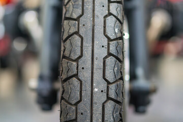 Close-up of a vintage sporty motorcycle wheel with radial spokes, patterned tread tire, and subtle shadows from depth of field No texts or logos visible