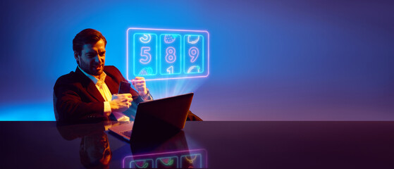 Businessman celebrating win at laptop with glowing slot machine interface. Concept of online gambling success, financial excitement, digital casino platforms, and risk driven decision making. Banner