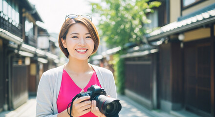 Joyful Asian woman with a camera smiles in a traditional Japanese street, capturing the essence of travel and exploration.