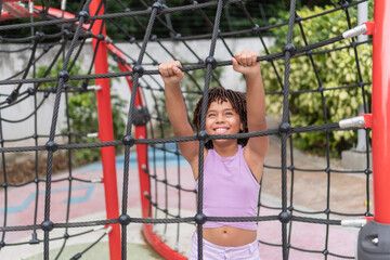 Happy black girl climbing on children's playground structure