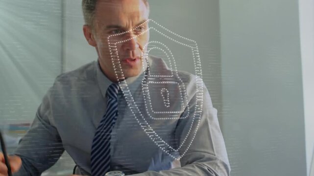 Animation of security padlock icon against caucasian businessman using computer and taking notes