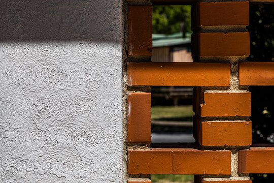 muro di cemento bianco attaccato ad un muro di mattoni con spazi vuoti, di giorno, in un ambiente urbano