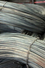 Close-up of coiled steel wire bundles stacked on the floor inside an industrial metal warehouse
