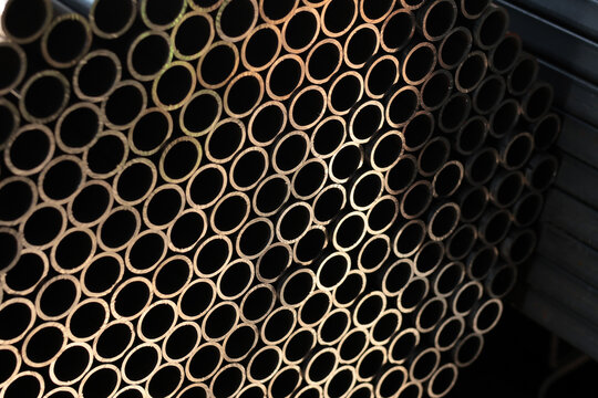 Close-up of stacked small diameter steel tubes forming a repeating circular pattern inside an industrial metal warehouse