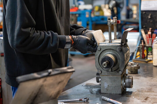 Vue sur une pi&egrave;ce m&eacute;canique et des composants m&eacute;talliques pos&eacute;s sur un &eacute;tabli dans un atelier industriel, illustrant un environnement de fabrication et d&rsquo;assemblage technique.