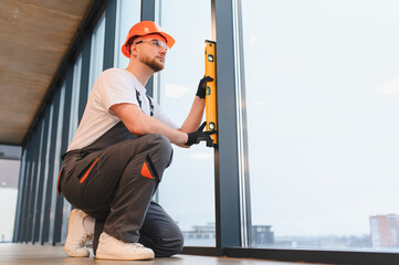 Construction worker installing window using spirit level