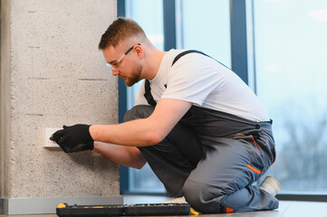 Electrician installing new power outlet in modern building