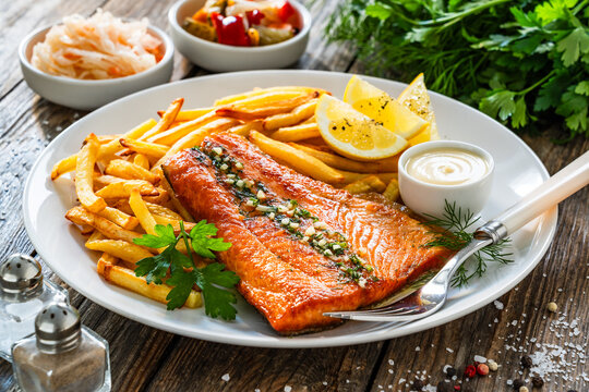 Fried salmon fillet with frites and mayonnaise on wooden table	