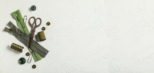 Different tailor's supplies with measuring tape on white grunge background with space for text