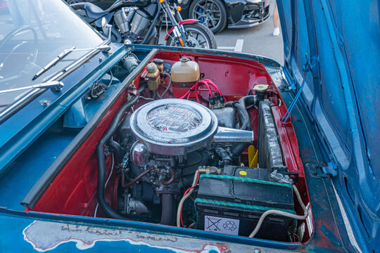 Close-up view of a VAZ 2101 Zhigulis engine compartment, dominated by blue and red shades, natural lighting, and detailed mechanical parts - Kyiv, Ukraine - September 21, 2025