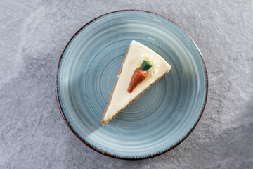 Carrot cake slice with cream cheese frosting on gray stone background. Top view