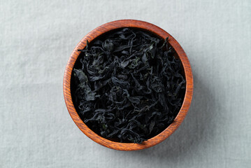 Top view of dried wakame seaweed in a wooden bowl on a fabric background, Healthy Asian food ingredient