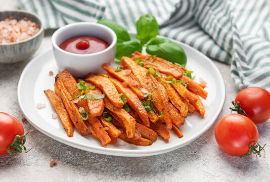 Sweet potato fries with ketchup and basil on plate