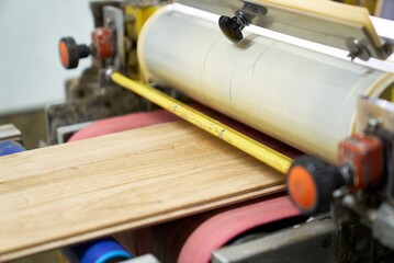 The process of calibrating or sanding a wooden board on an industrial drum sander.