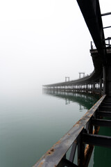 Fototapeta premium Tinto River dock under the fog. Huelva. Vertical composition