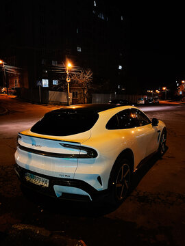 White Xiaomi YU7 SUV parked on a quiet urban street at night with warm streetlights and modern design