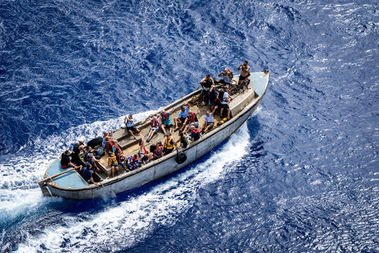 Adamstown, Pitcairn Islands - 21 February 2019: View of a boat slicing through the deep blue sea, carrying people under the vast, open sky, the white wake contrasting with the dark water.