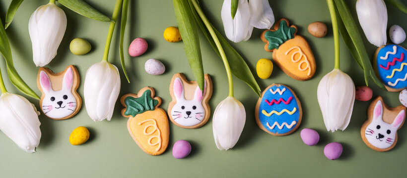 Easter banner, spring holiday background with easter cookies: buny, carrot and egg with white tulip flowers, flat lay