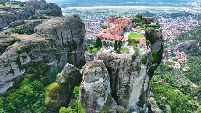 Aerial drone footage orbiting the Monastery of the Holy Trinity in Meteora, Greece. Cinematic close-up of the iconic UNESCO World Heritage site perched on a dramatic cliff rock