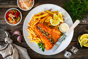 Fried salmon fillet with frites and mayonnaise on wooden table. Top view