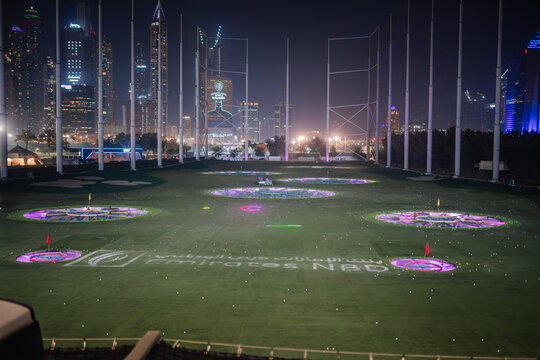 Topgolf Dubai illuminated driving range at night with city skyline and colorful target zones visible