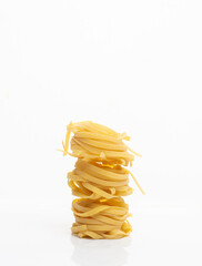Dry tagliatelle pasta on a white background