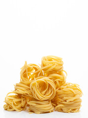 Dry tagliatelle pasta on a white background