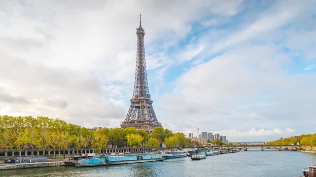 A time lapse of the Eiffel Tower along the river Seine with flyboats passing. Sunny but cloudy autumn day with golden yellow leaves,paris city riverside bay view bridge. Eiffel tower in Paris, France
