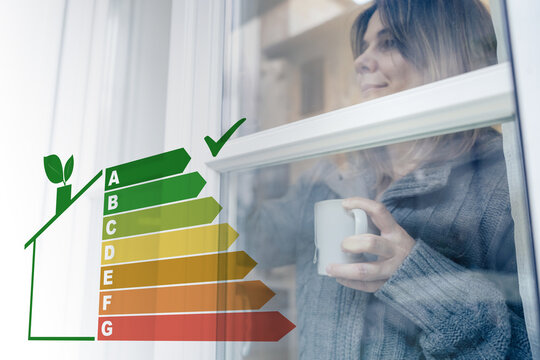 Woman with a warm mug looks through an energy efficient window featuring an overlaid energy rating scale demonstrating high thermal insulation and eco friendly home improvements for saving money