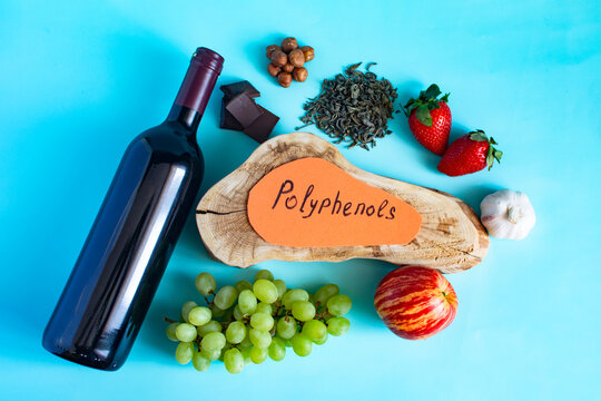Products containing useful polyphenols in their composition. Grapes, garlic, chocolate, green tea, nuts, strawberries, red wine in close-up on a light background and the inscription "polyphenols".