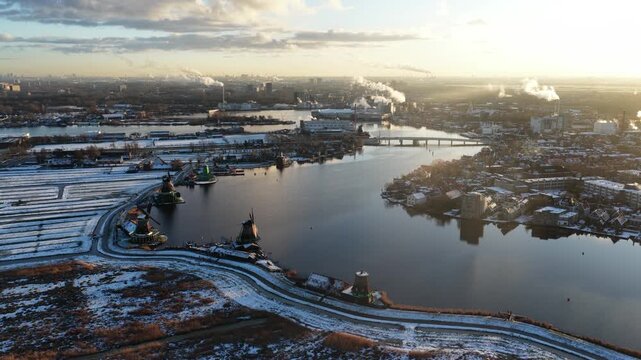 Aerial drone view of the Zaanse Schans windmills along the Zaan river in a white winter landscape, showing Dutch heritage, culture, and traditional polder scenery.