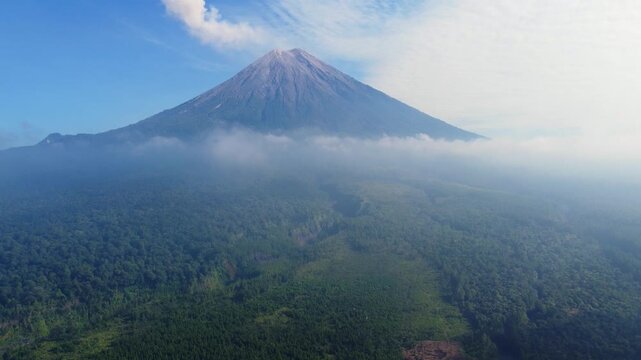 Stone river, stone deposit and Mount Semeru. Volcano clouds of smoke against the blue sky. Active volcano on the island of Java in Indonesia. Ash pillar from a bird's eye view. Dron. 4K