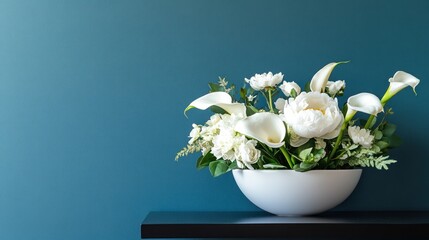 Elegant white floral arrangement with lush peonies and calla lilies in a ceramic vase on a teal shelf