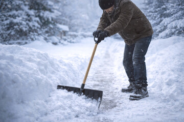 Man clearing snow on winter pathway