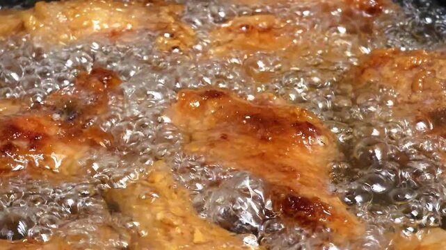 Close up of chicken wings frying in hot boiling oil with bubbles