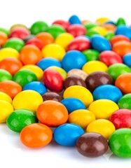 Pile of small, colorful, round candies on a white surface, creating a vibrant and delicious-looking array