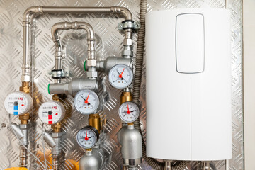 Water heating system with pressure gauges and pipes mounted on a metallic wall, featuring a modern...